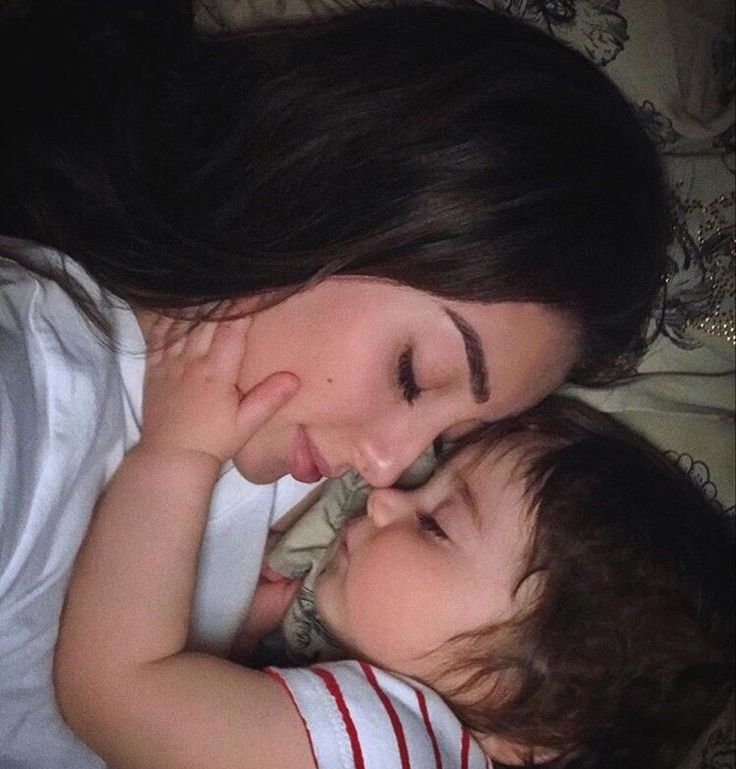 a woman and child laying on top of a bed next to each other with their eyes closed