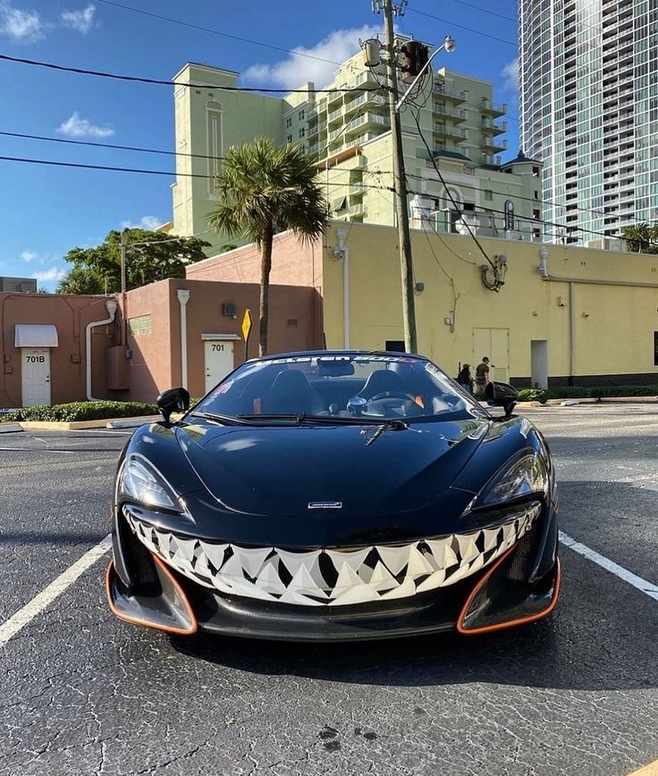 a black sports car parked on the side of the road in front of tall buildings