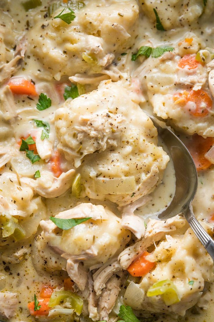 a close up of a spoon in a bowl of chicken and dumplings with broccoli