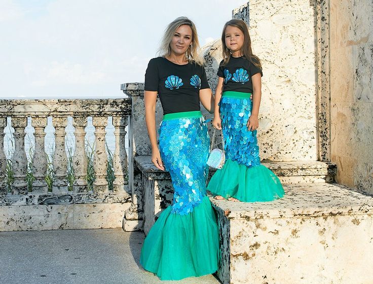 two beautiful women standing next to each other in front of a stone wall and railing