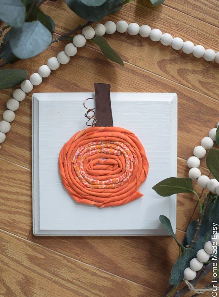 an orange piece of art sitting on top of a wooden floor next to some flowers