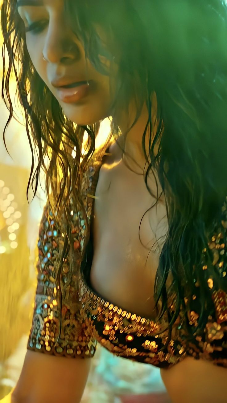 a close up of a woman with long hair wearing a gold dress and holding a cell phone to her ear