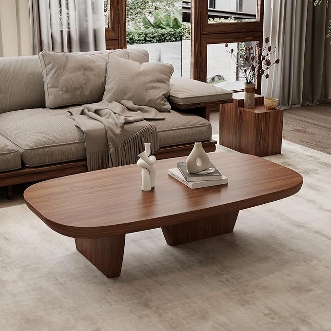 a living room with couches, coffee table and vases on the floor in front of large windows