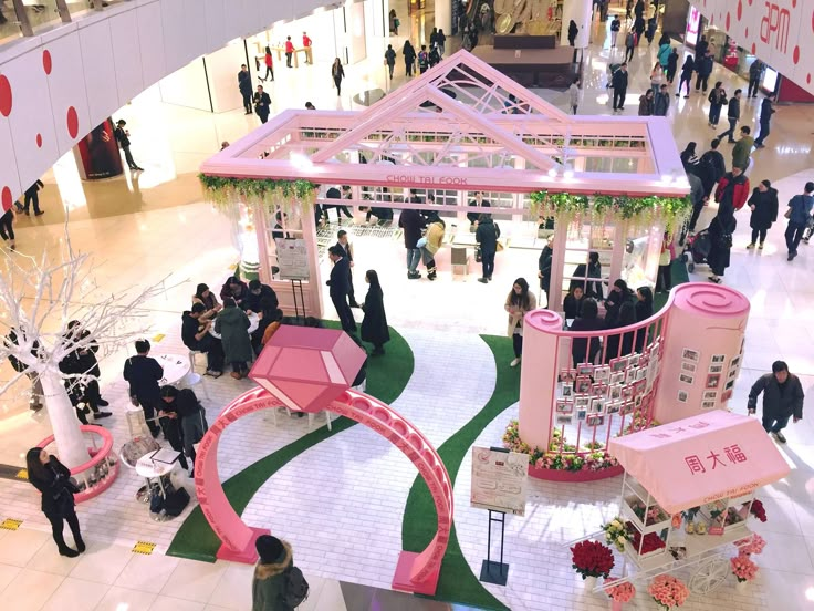 an overhead view of people walking around in a shopping mall with pink and white decorations