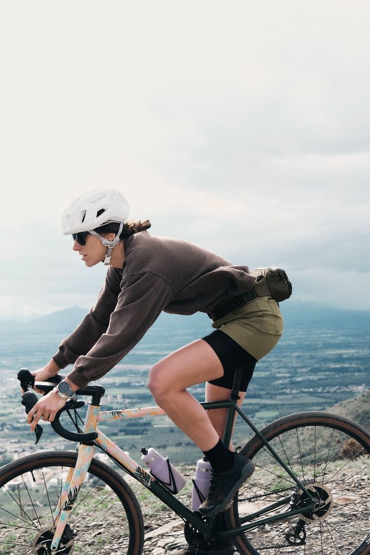 a woman riding a bike on top of a mountain