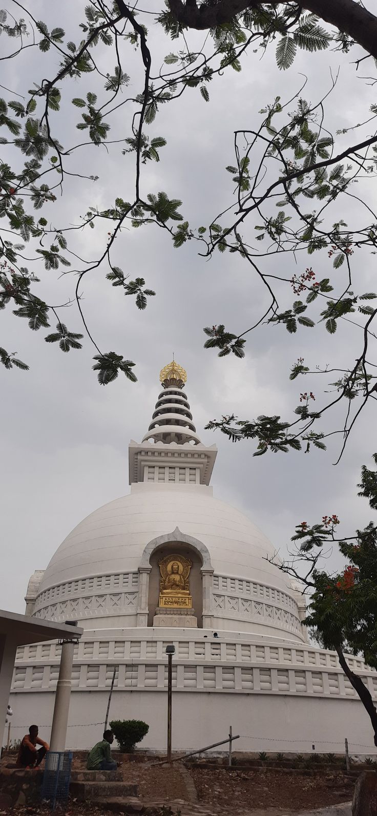 a large white building with a golden statue on it's side and trees in the foreground