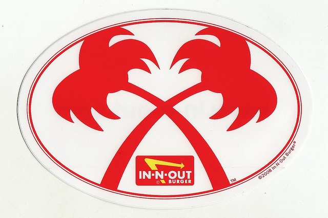 a red and white sticker with two palm trees in the center on a yellow wall