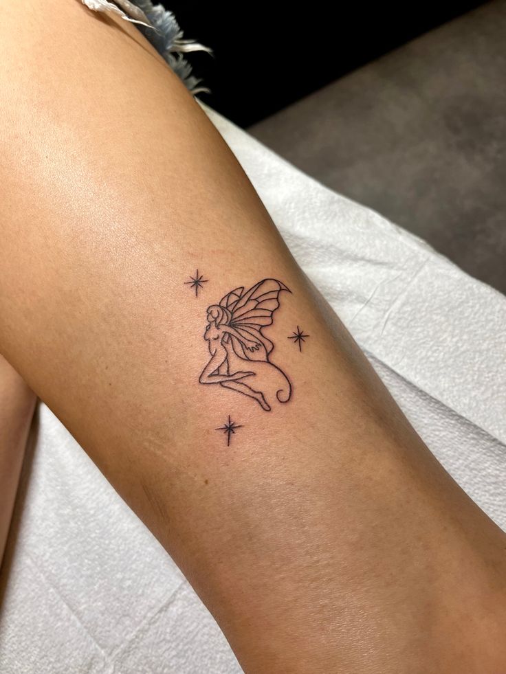 a woman's arm with a small fairy tattoo on the back of her leg