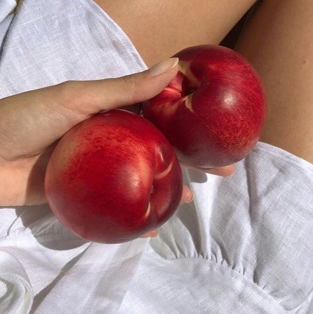 two apples being held in the palm of someone's hand on a white sheet