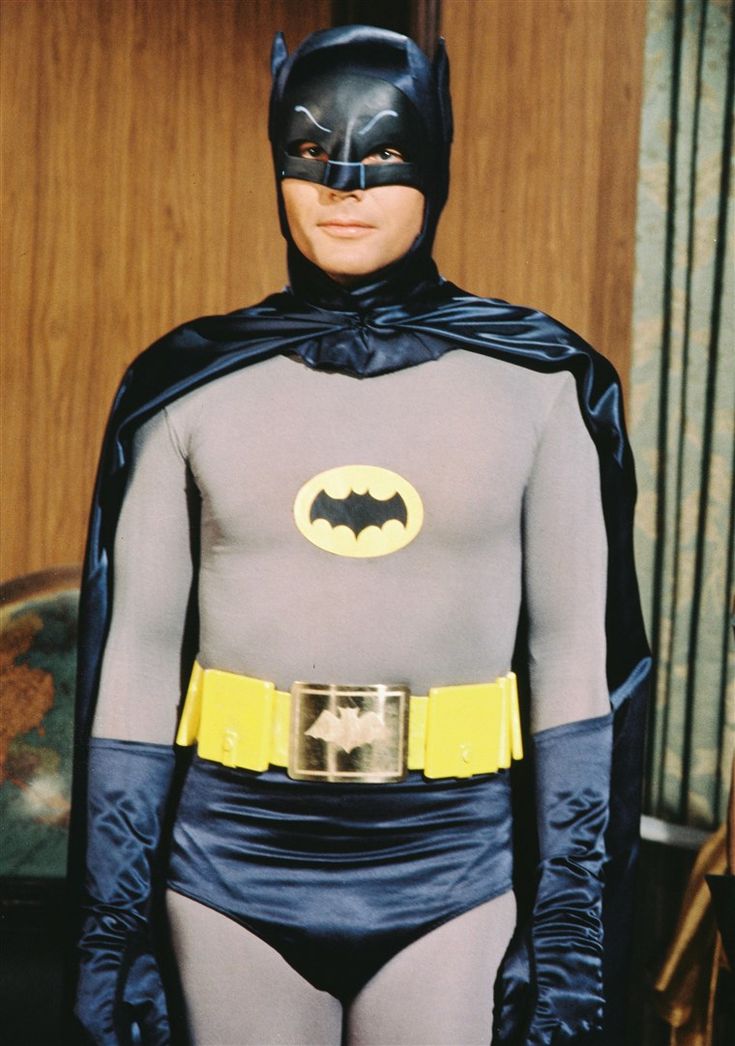 a man in batman costume standing next to a bed