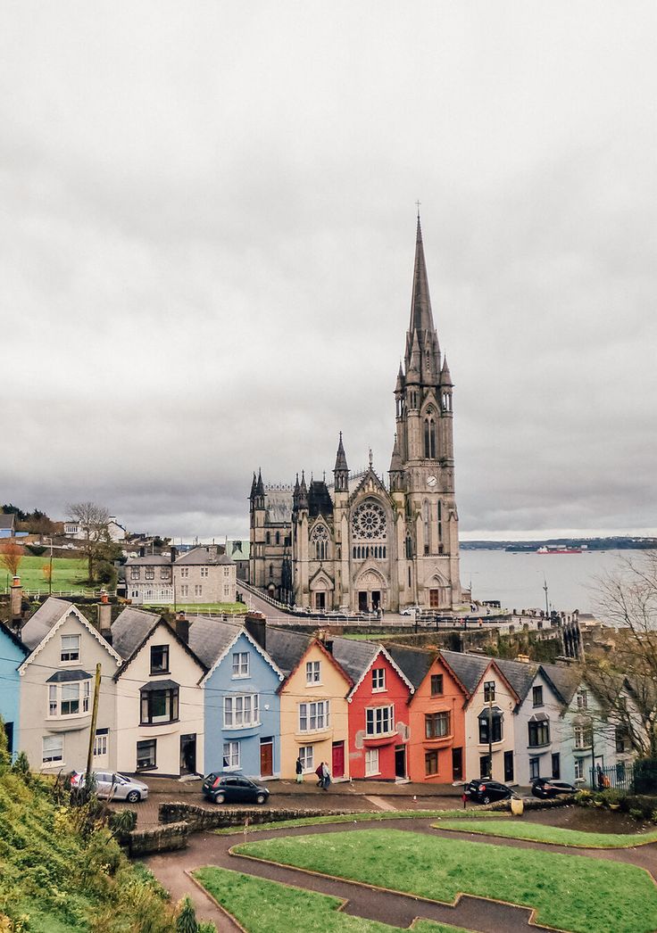 a group of colorful houses with a church in the back ground and water behind them