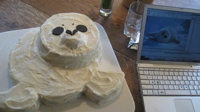 a cake shaped like a polar bear sitting on top of a plate next to a laptop computer