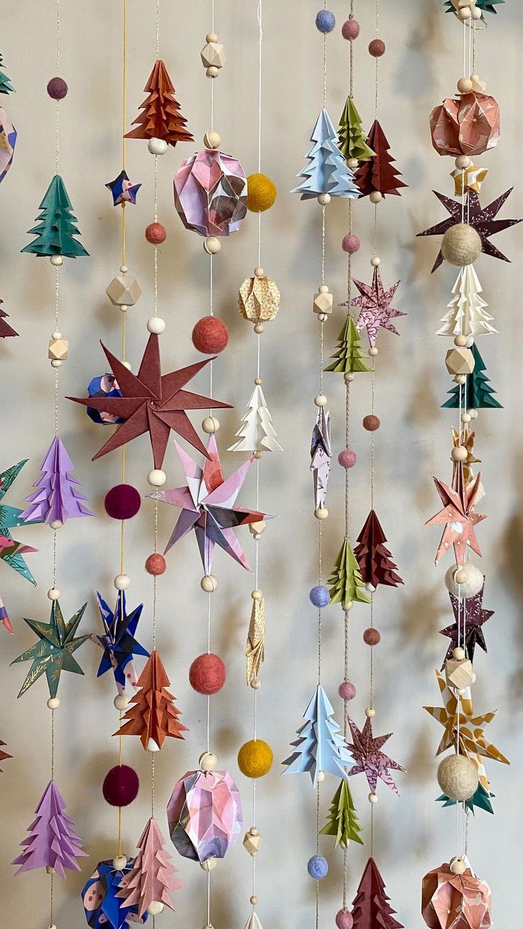 an origami christmas tree mobile hanging on a wall with ornaments and baubles