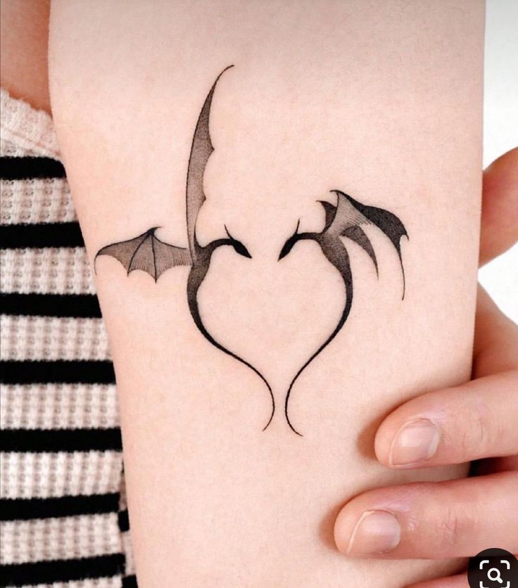 a woman's arm with a tattoo on it that is shaped like a bat