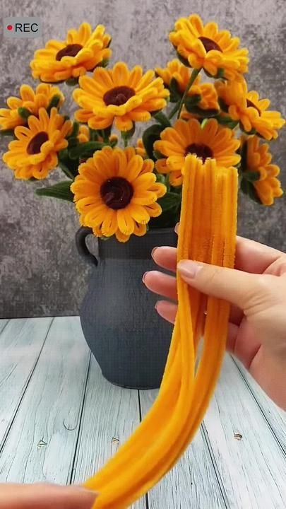 someone is holding some yellow flowers in their hand