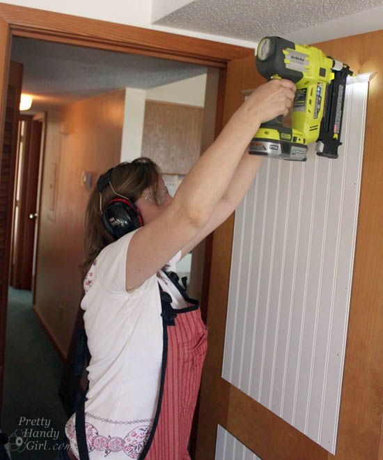 a woman is using a driller on the wall in her house while wearing headphones