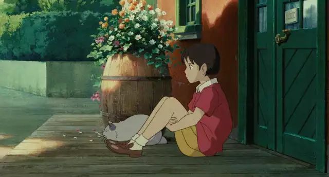 a person sitting on the ground next to a potted plant with flowers in it