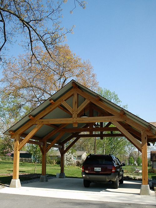 a car is parked under a wooden covered structure in the middle of a park area