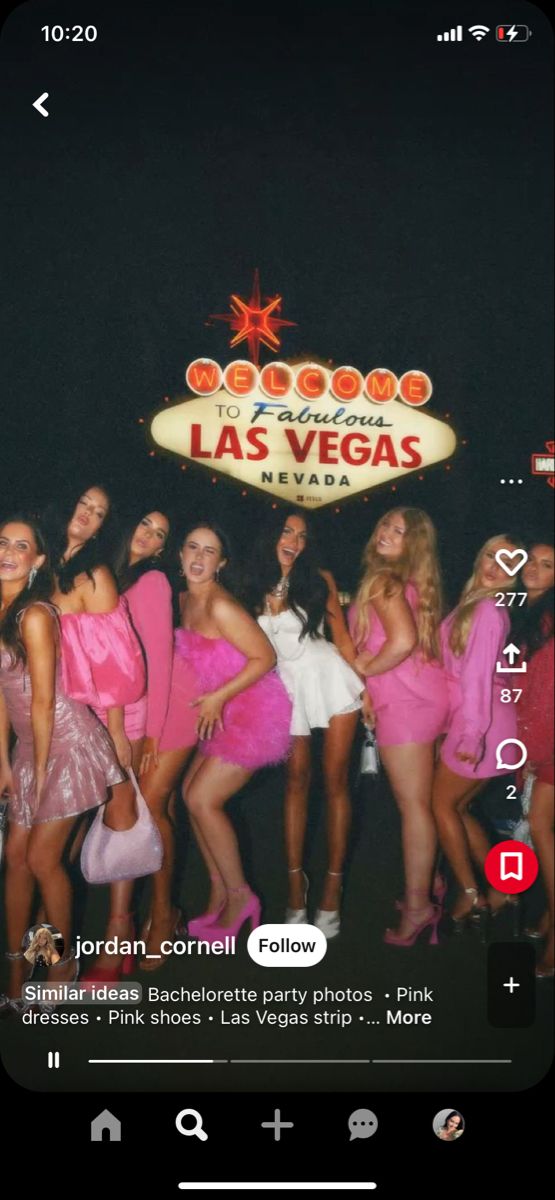 a group of women in pink dresses posing for a photo at the las vegas sign