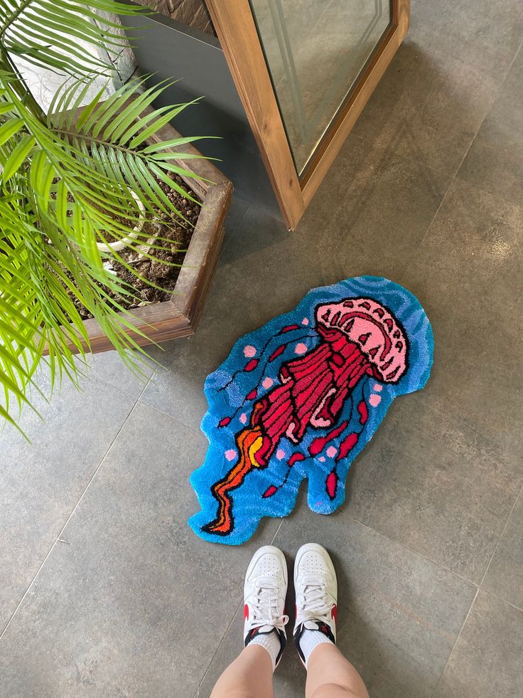 a person standing next to a potted plant and a rug with a cartoon character on it