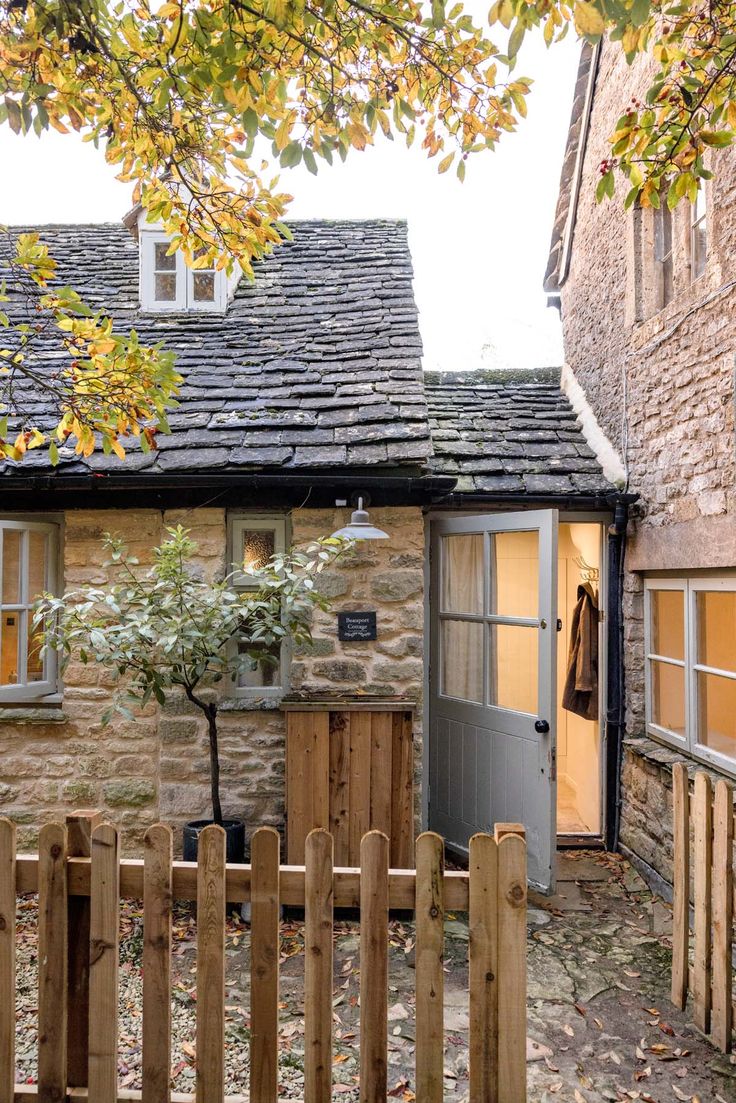 an old stone building with a wooden fence and potted plant in the front yard