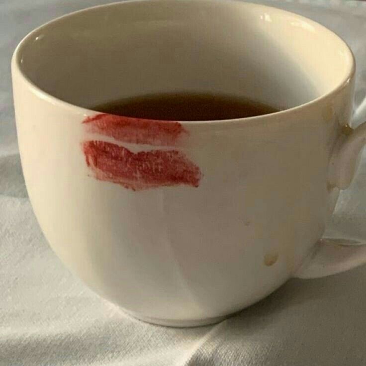 a white cup filled with liquid on top of a white tablecloth covered table cloth