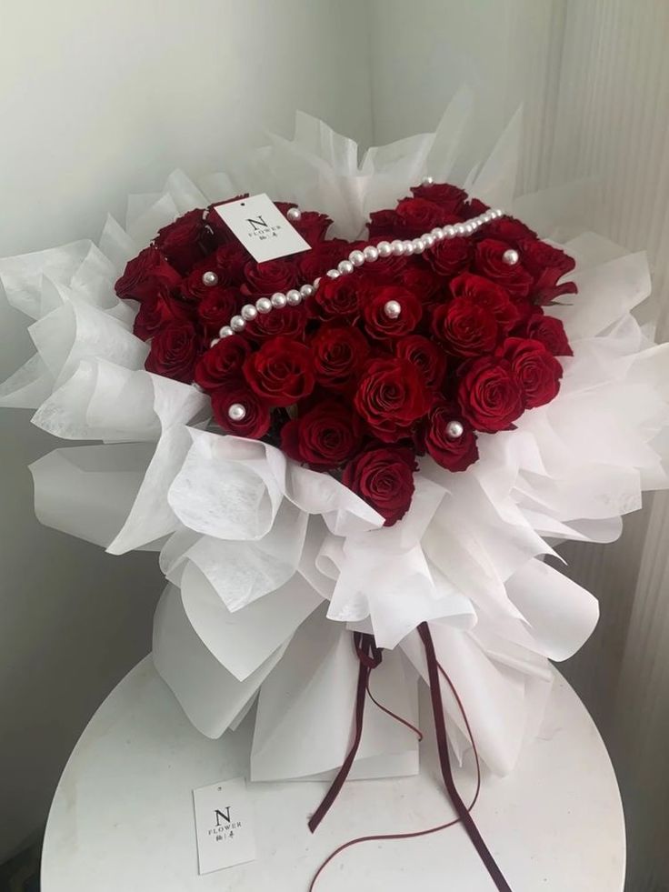 a bouquet of red roses in the shape of a heart on top of a table