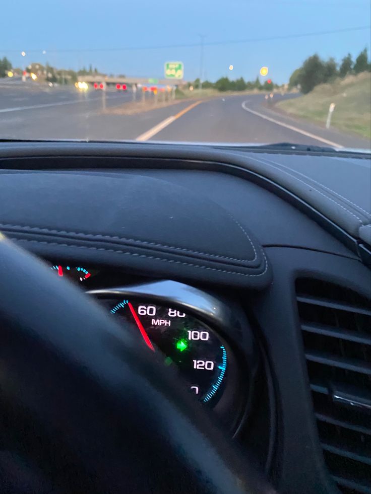 the dashboard of a car on a highway with traffic lights and speedometers visible