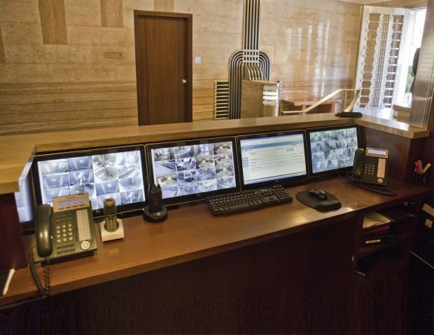 three computer monitors sitting on top of a wooden desk next to a phone and keyboard