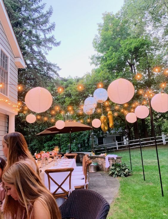 a group of people sitting around a table with paper lanterns hanging from it's ceiling