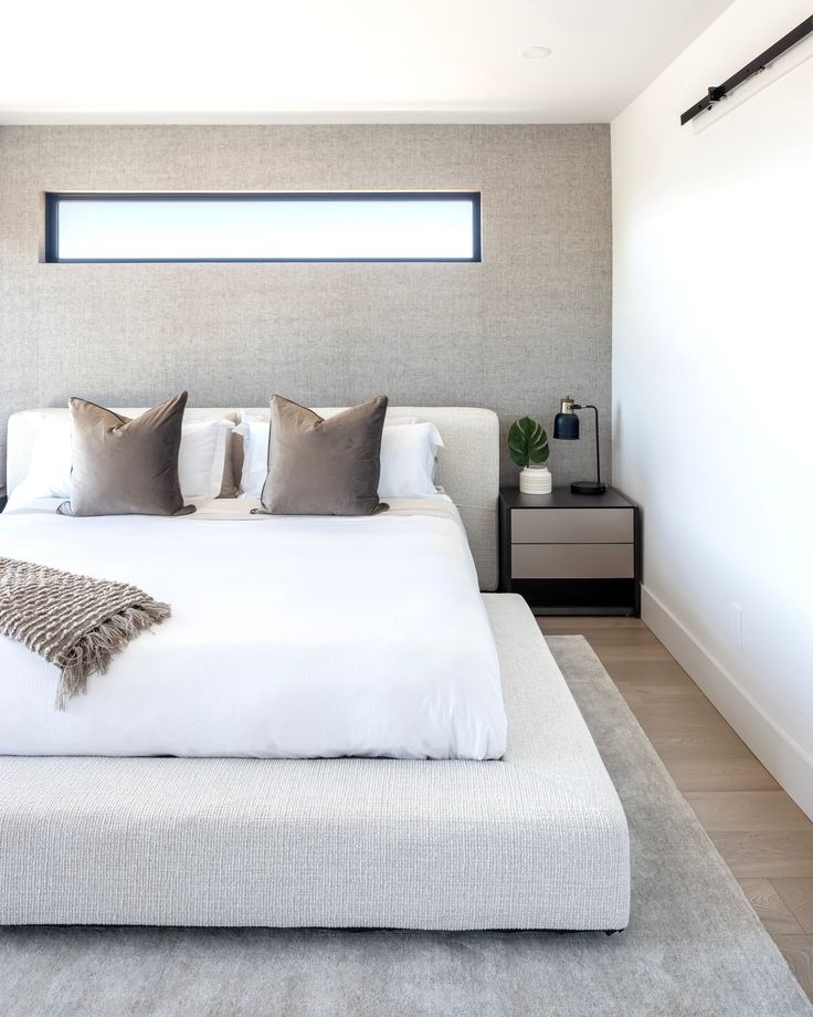 a white bed sitting in a bedroom on top of a hard wood floor next to a window