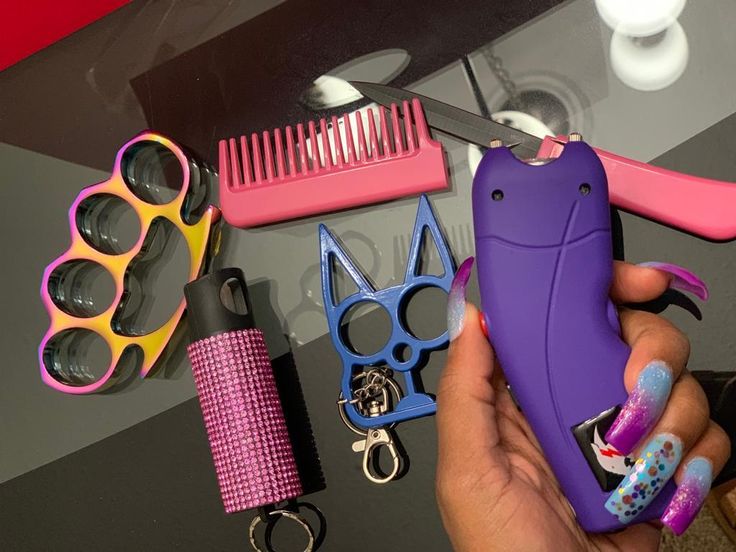 a person holding a purple case next to some scissors and other items on a table