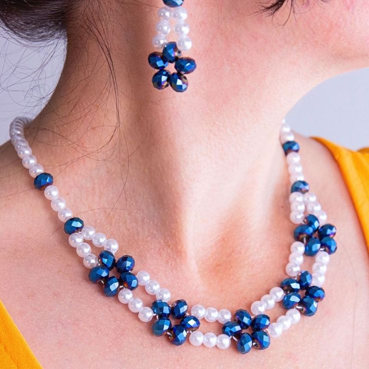 a woman wearing a blue and white necklace and earring with pearls on her neck