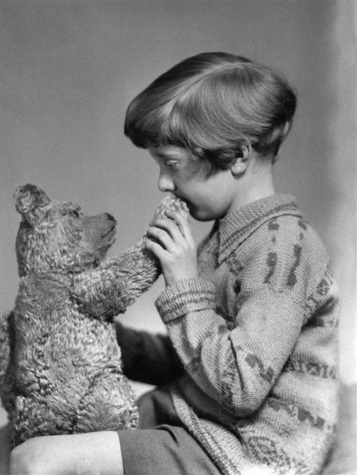 an old black and white photo of a young boy holding a teddy bear in his hands