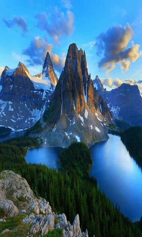 the mountains are covered in snow and have blue water on them, as well as green trees