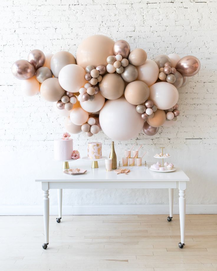 a table topped with lots of balloons on top of a white brick wall next to a wooden floor