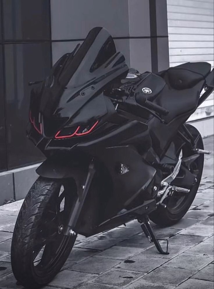 a black motorcycle parked on the sidewalk next to a building