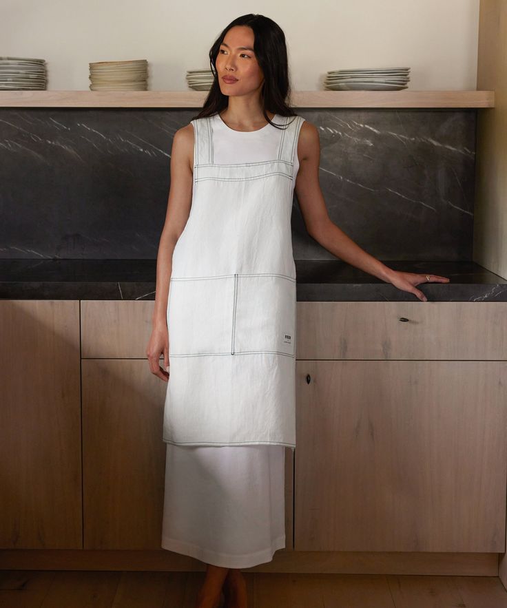 a woman standing in front of a counter with plates on it and bowls behind her