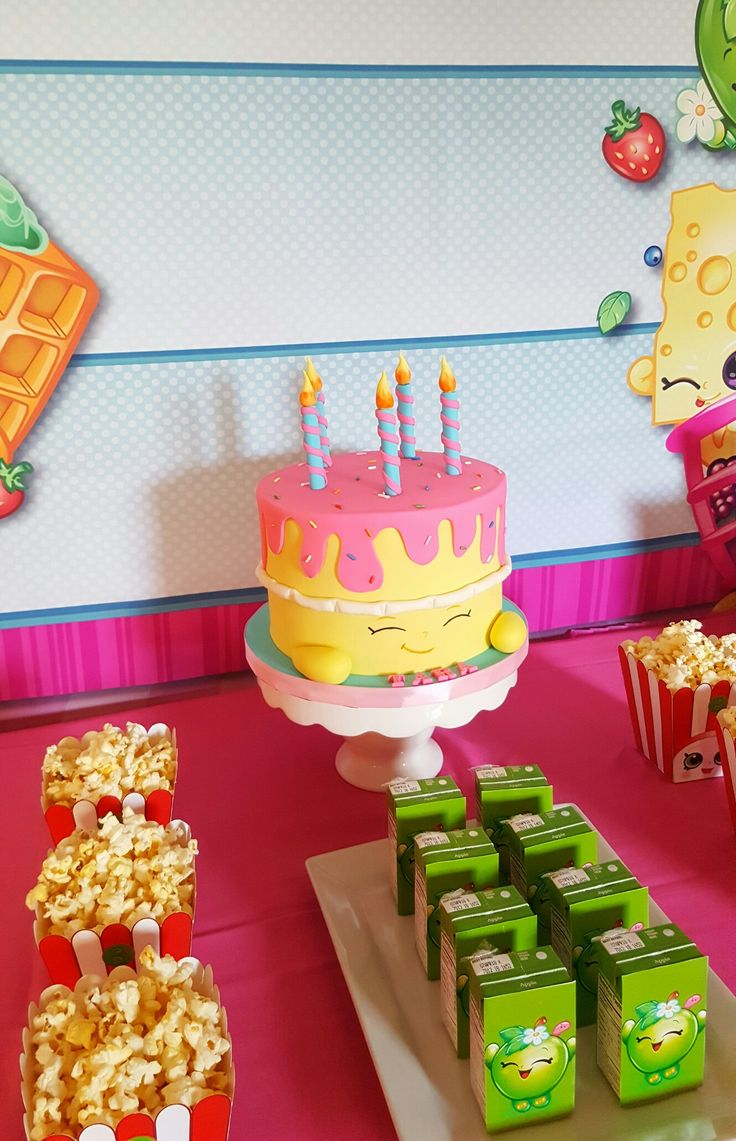 a birthday cake with candles on it sitting next to popcorn boxes and other items in front of the cake