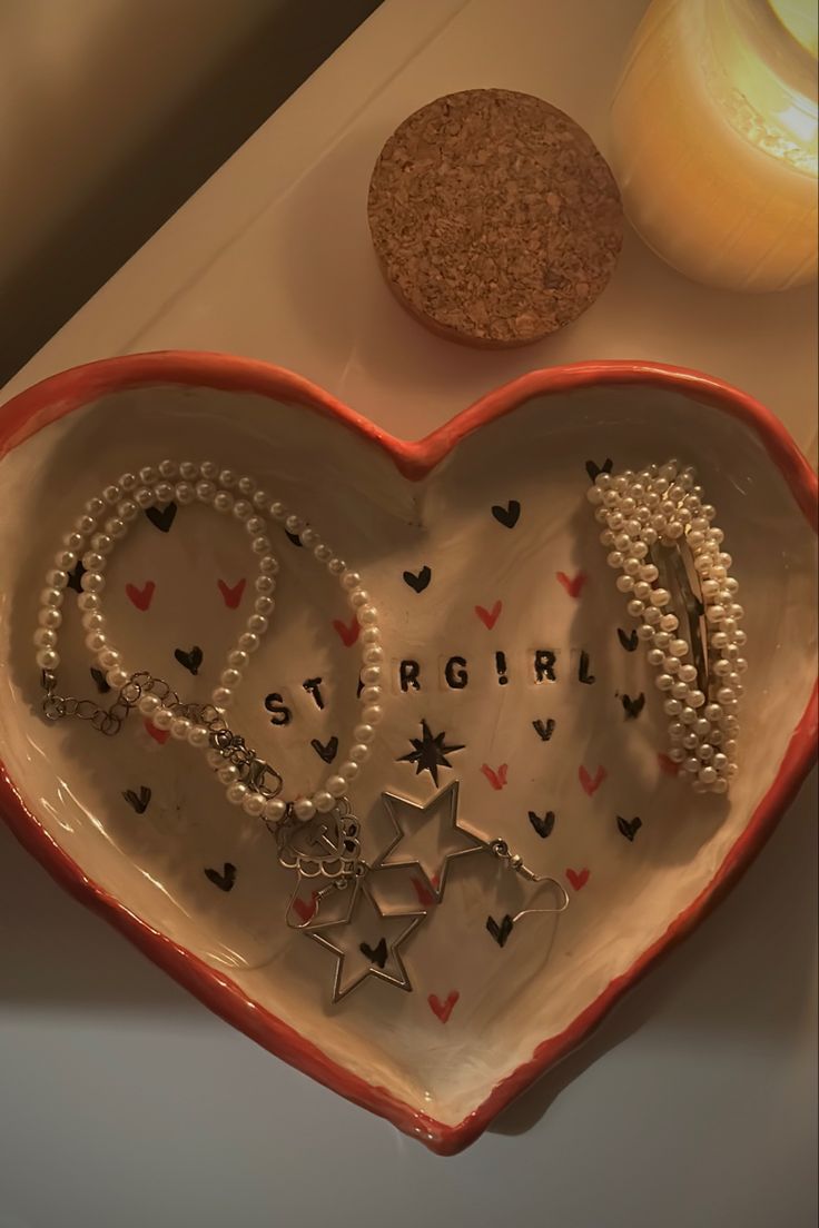 a heart shaped dish with two bracelets on it