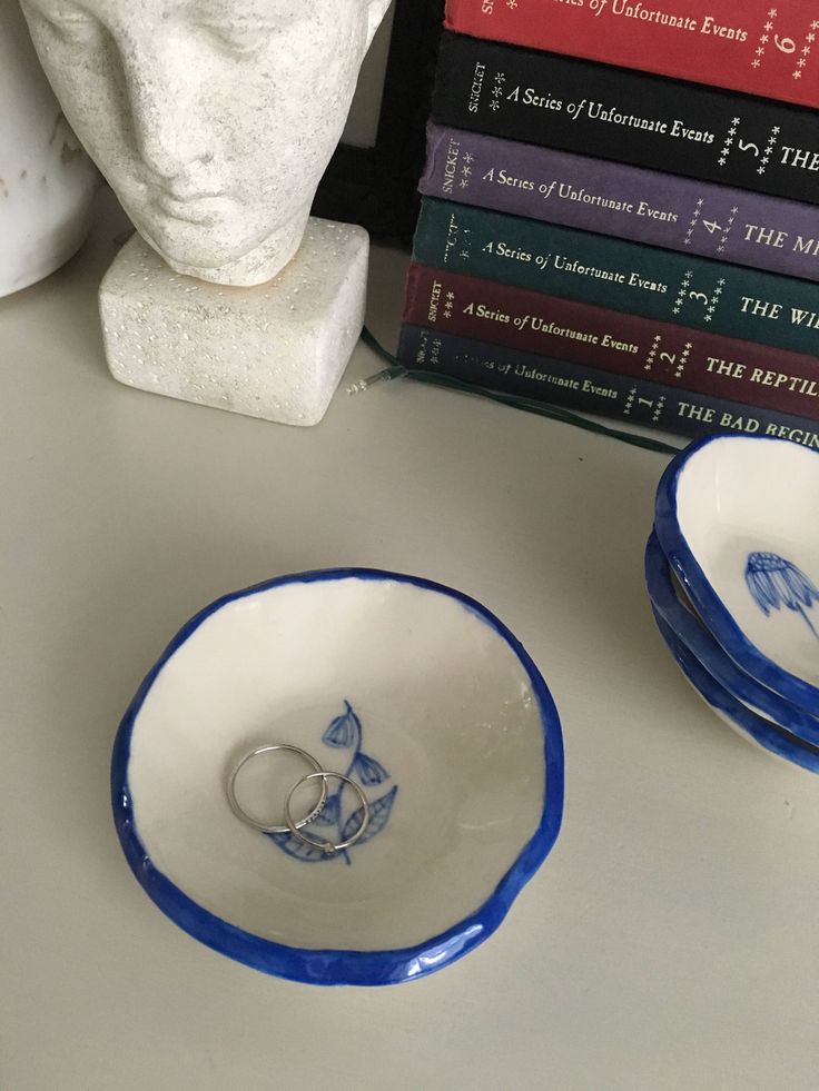 two blue and white bowls sitting on top of a table next to bookshelves