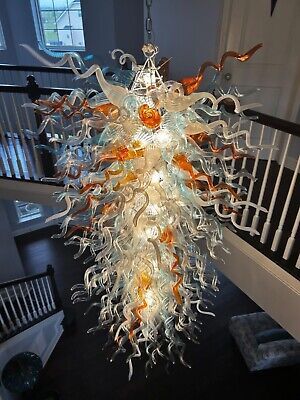 a chandelier hanging from the ceiling in a room with stairs and railings