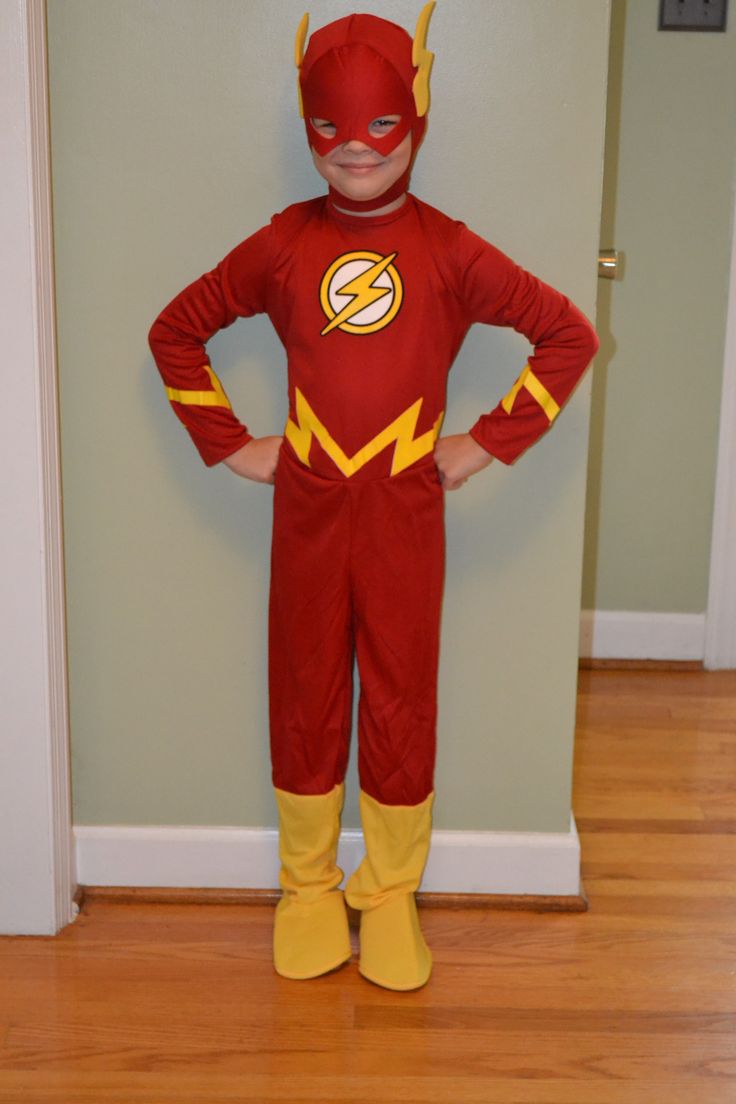 a young boy dressed as the flash standing in front of a door