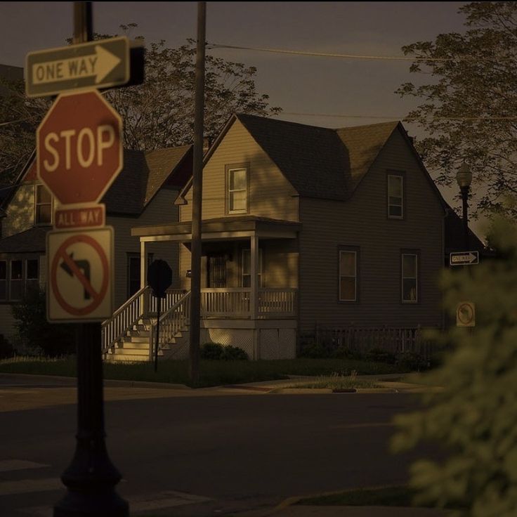 a stop sign and no right turn sign in front of a two story house at night