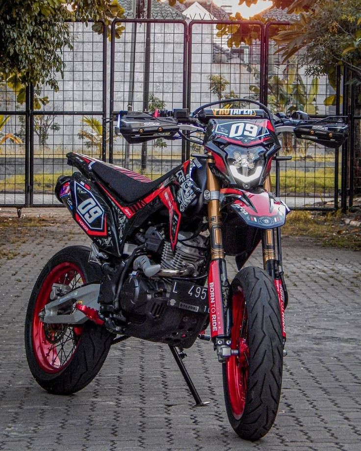 a red and black dirt bike parked in front of a fence