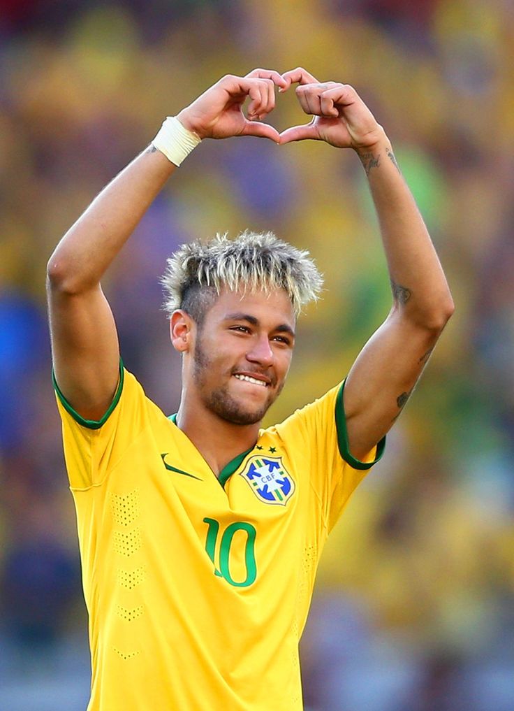 a man with his hands in the air making a heart shape while wearing a yellow shirt