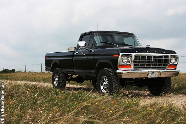 a black truck parked in the middle of a field