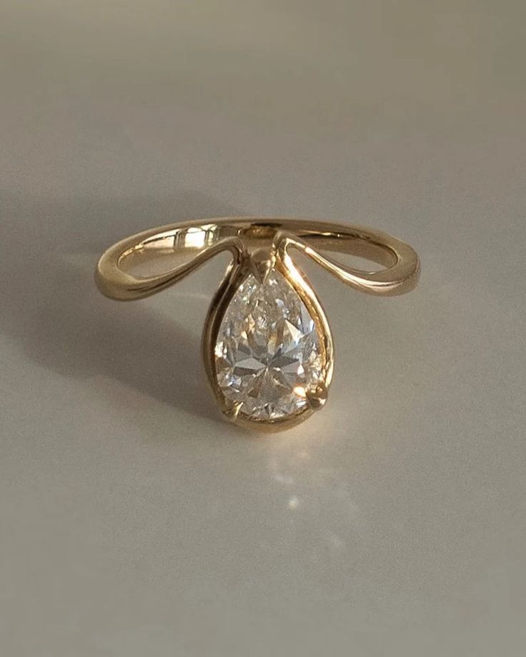 a yellow gold ring with a pear shaped diamond