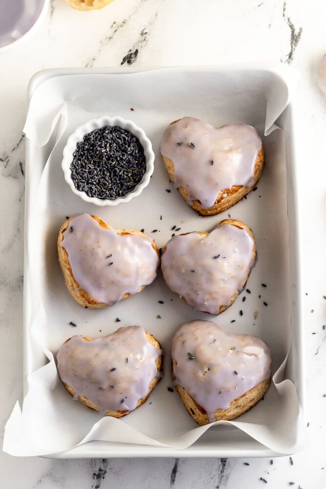 four donuts with icing and sprinkles in a white tray on a marble table