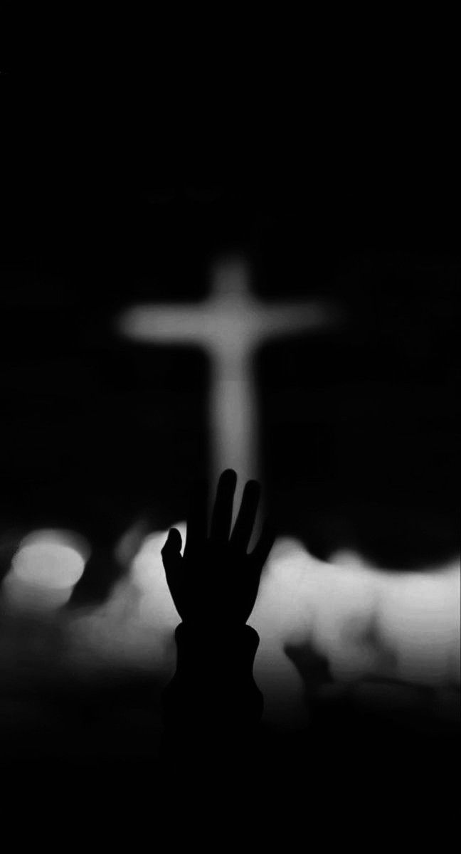 a person holding their hand up in front of a cross